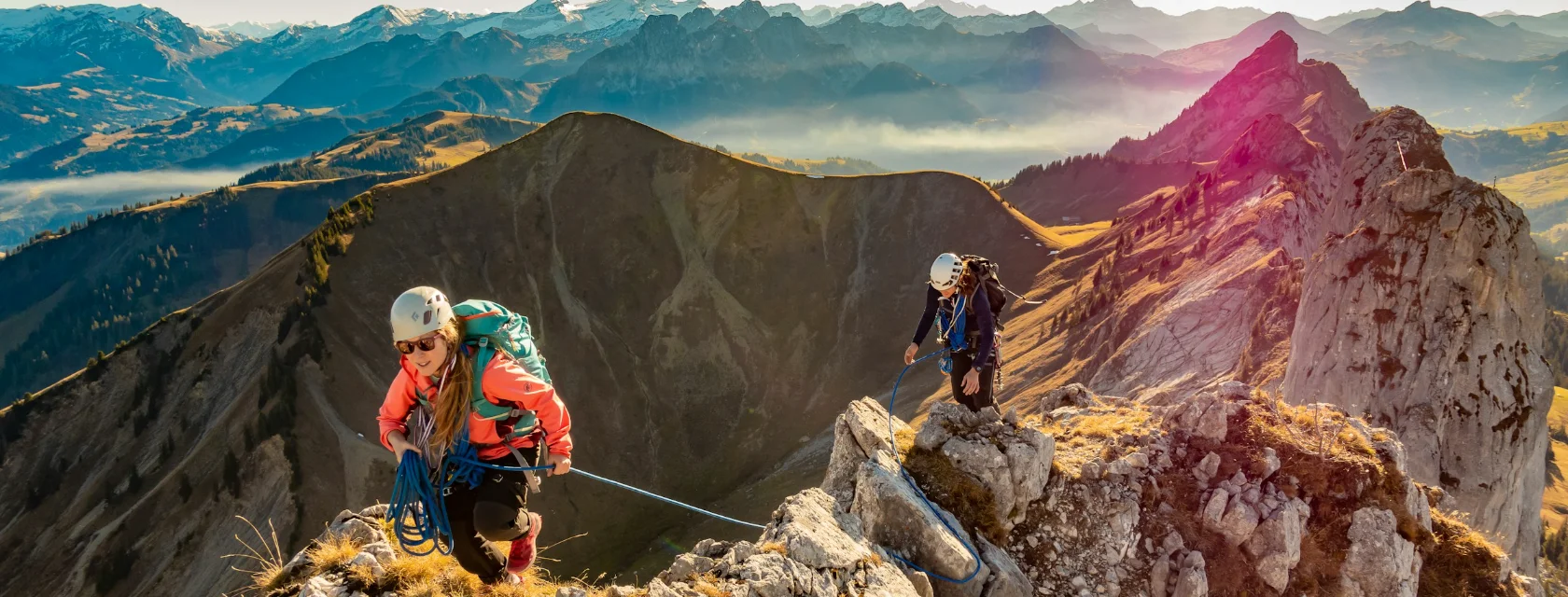 Duas pessoas encordoadas subindo uma crista de montanha nos Alpes suíços, ao entardecer