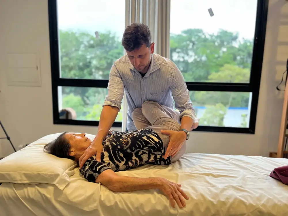 Terapia manual com a paciente deitada na maca, junto à janela
